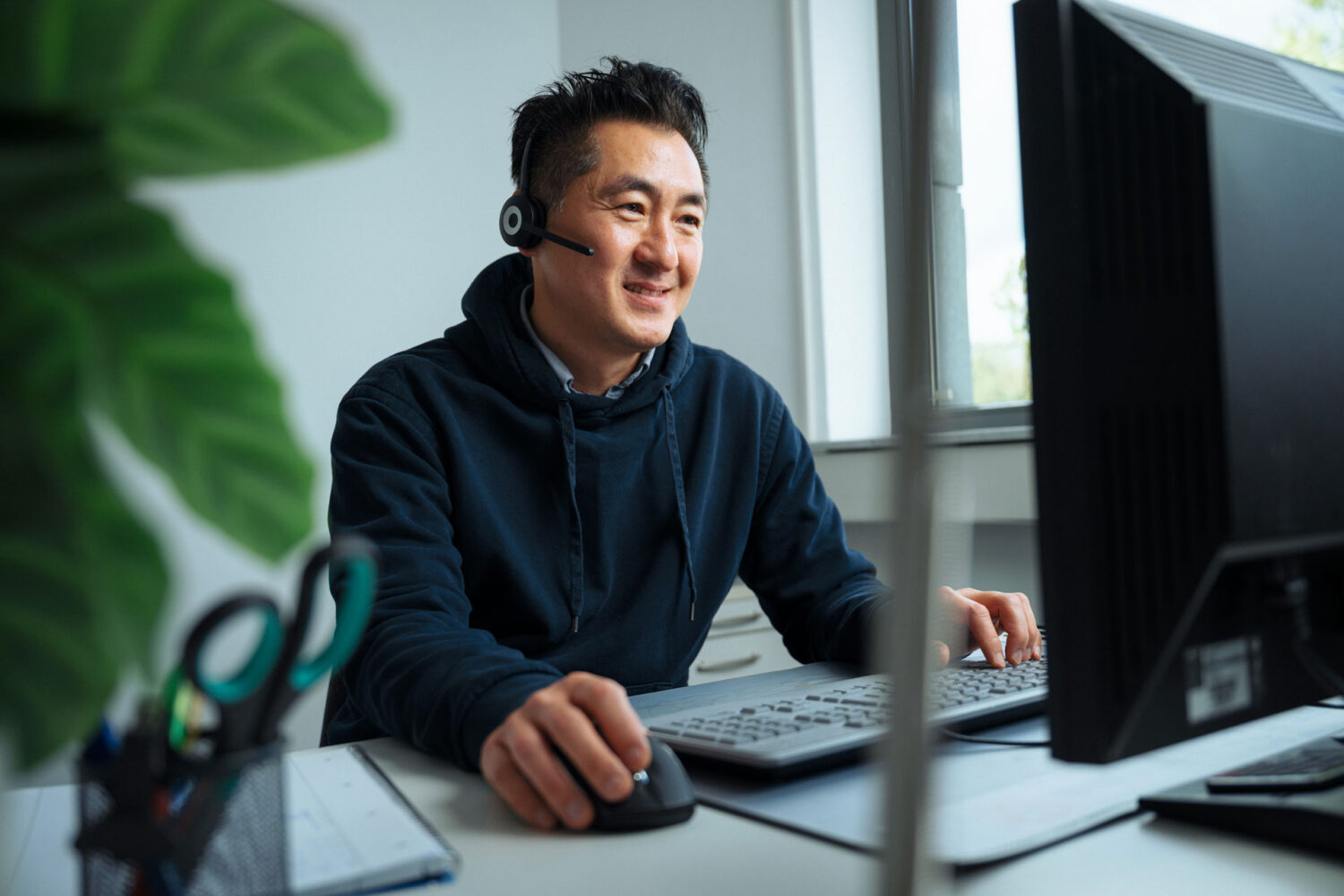 syniqo Mitarbeiter mit Headset am Schreibtisch