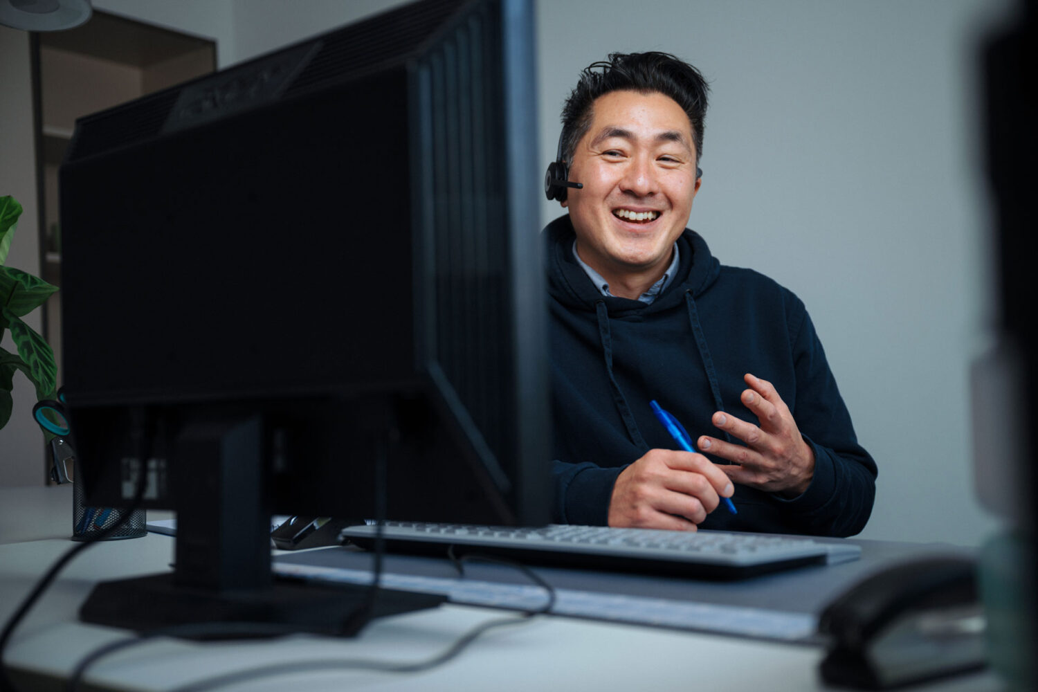 Support-Mitarbeiter mit Headset hilft bei Rückfragen zur Telekommunikation in Unternehmen